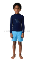 Boy wearing a long-sleeve rash guard with glowing manta ray print and swim shorts