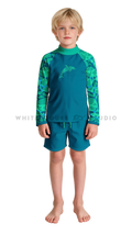 Boy wearing a long-sleeve rash guard with teal dolphin ripple print and swim shorts