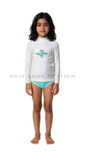 Girl wearing a long-sleeve rash guard with blue shadow manta print and bikini bottoms