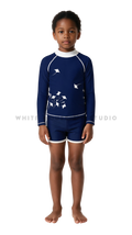 Girl wearing a long-sleeve rash guard with dark blue manta group print and swim shorts