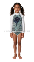 Girl wearing a long-sleeve rash guard with green ripple manta print and bikini bottoms