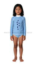 Girl wearing a long-sleeve rash guard with ocean blue manta group print and bikini bottoms