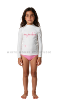 Girl wearing a long-sleeve rash guard with pink magical manta print and bikini bottoms